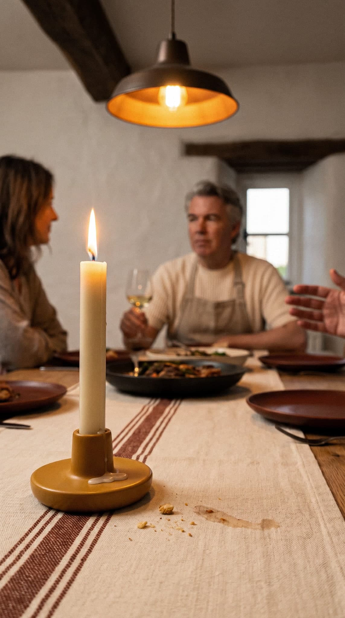 Friends gathered around a candlelit festive table with wine and shared dishes