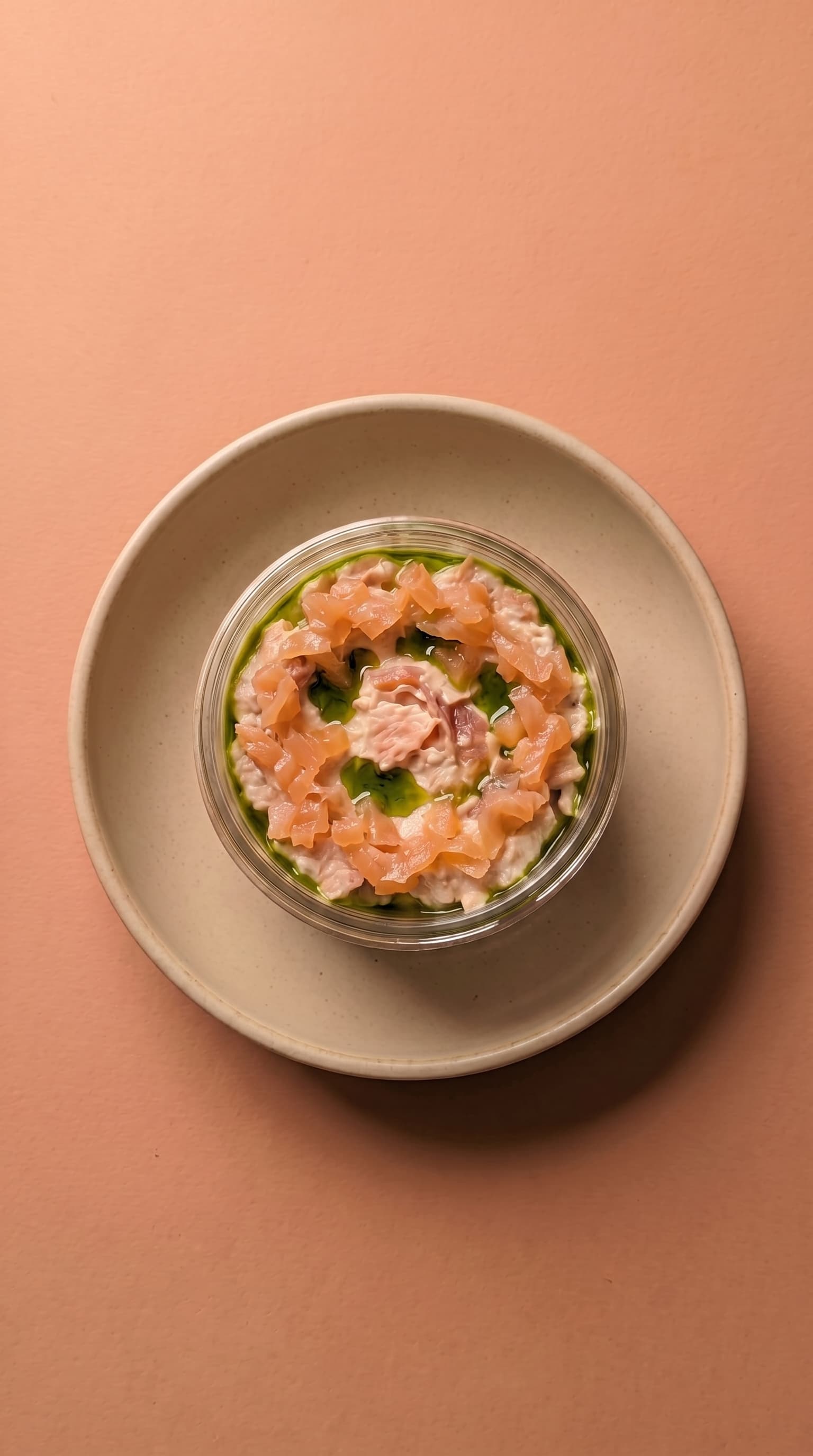 Rillettes de saumon onctueuses avec morceaux de saumon fumé, huile verte et herbes dans un bol en verre