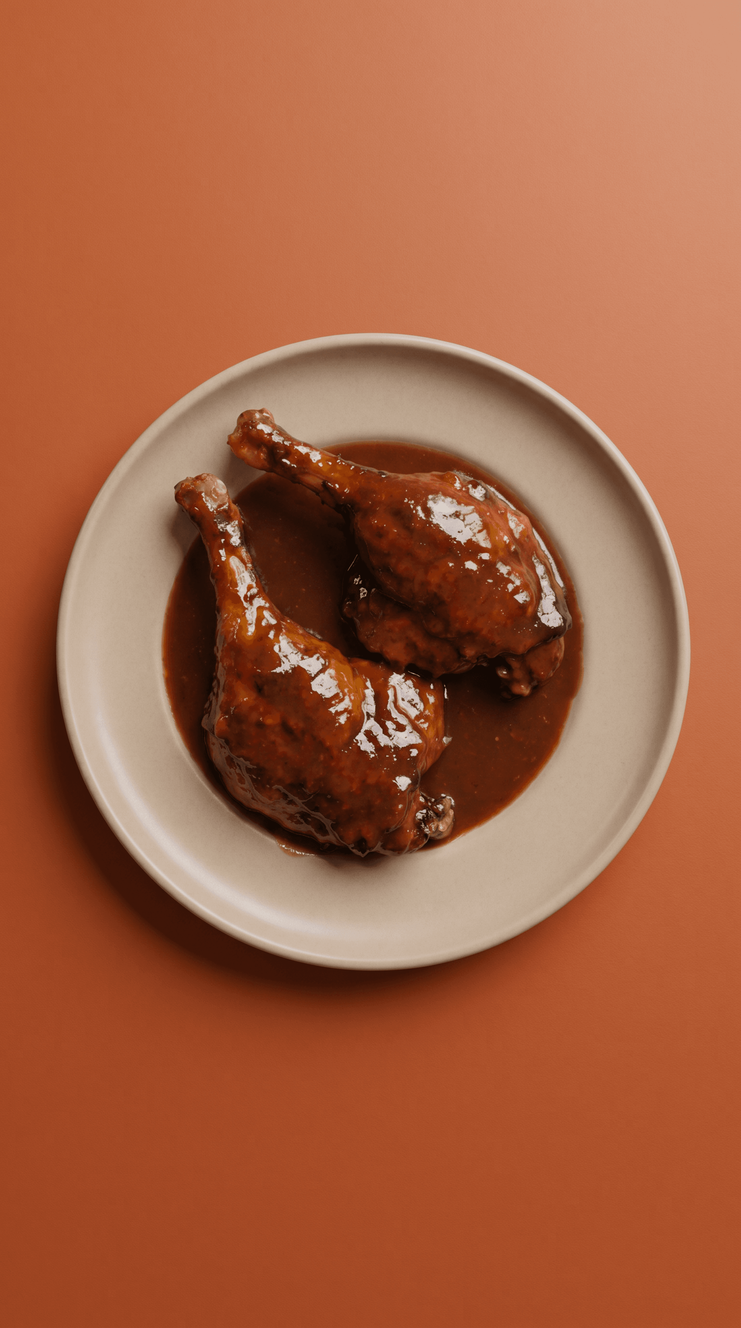 Vue de dessus de deux cuisses de canard laquées au gochujang brillantes avec leurs manchons, reposant dans une sauce épaisse et foncée sur une assiette en céramique beige sur un fond terracotta chaleureux